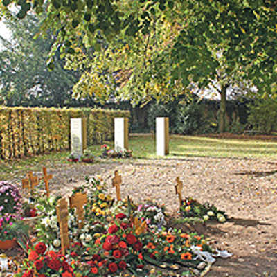 Auf dem Hauptfriedhof werden seit 2010 Urnen unter einem alten Baum bestattet. Namenstafeln werden an Sandsteinstelen (hinten) angebracht. Holzkreuze erinnern an kürzlich Verstorbene. Für sie werden später weitere Stelen errichtet.