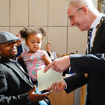 Der gebürtige Nigerianer Fabian Akpan freut sich mit seiner in Deutschland geborenen Tochter Thalia über die Einbürgerungsurkunde von OB Wolfram Leibe. 