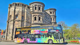 Ein Doppeldeckerbus für touristische Stadtrundfahren fährt an der Porta Nigra vorbei.
