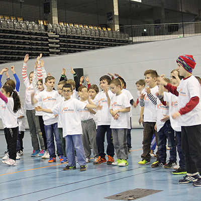 Initiator Theo Lamberts animiert zum symbolischen Start der Aktion in der Arena einige Flüchtlingskinder und Altersgenossen von der Ausonius-Grundschule zu einer Gymnastikübung. 