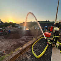 Die Feuerwehr spritzt auch aus gebührender Entfernung den Sand über der Bombe nass.