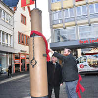 Karlheinz Scheurer und Markus Nöhl entfernen zur offiziellen Übergabe des restaurierten Prangers die Geschenkschleife.