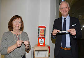 Bürgermeisterin Elvira Garbes und OB Wolfram Leibe präsentieren den Sticker und das Schriftband mit QR-Code, die in einer Kapsel aus dem roten Automaten gezogen werden können.