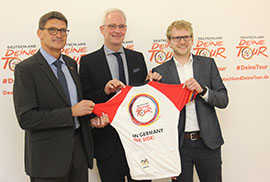OB Wolfram Leibe (Mitte) und Landrat Günther Schartz (l.) präsentieren mit Matthias Pietsch, Projektmanager des Veranstalters ASO (r.), das offizielle Trikot der Deutschland-Tour 2018. OB Wolfram Leibe (Mitte) und Landrat Günther Schartz (l.) präsentieren mit Matthias Pietsch, Projektmanager des Veranstalters ASO (r.), das offizielle Trikot der Deutschland-Tour 2018.