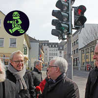 OB Wolfram Leibe, Baudezernent Andreas Ludwig und Zeichner Johannes Kolz (v. r.) freuen sich über den gelungenen Start der neuen Ampelmännchen am Simeonstiftplatz