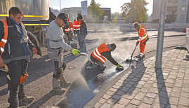 Mitarbeiter der Firma Schnorpfeil präparieren die Entwässerungsrinne am neuen Römerbrückenkreisel in Trier-West mit heißem Gussasphalt. 