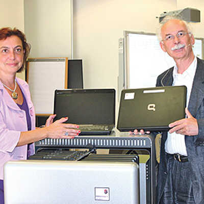 Rudolf Hahn, Leiter des städtischen Bildungs- und Medienzentrums, und Dozentin Dr. Ute Kreisel präsentieren den Rollwagen mit zwölf Laptops.