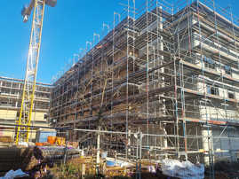 Blick auf die Baustelle mit dem eingebrüsteten Gebäude für neue Wohnungen und die Kita. Sie liegt in der Nähe des Bürgerhauses und der Ambrosius-Grundschule 