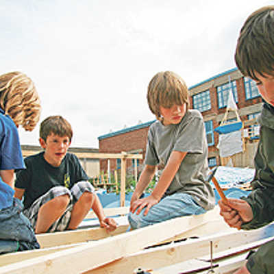 Mit Hammer und Nagel befestigen diese Jungs Holzlatten auf dem Dach der „Tufatopolis“-Bar. Das Werkzeug und Material wird den Kindern zur Verfügung gestellt. Was und wie gebaut wird, bestimmen die kleinen Baumeister selbst.