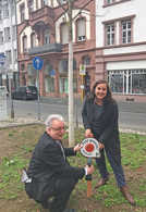 Dezernent Andreas Ludwig und die Leiterin des Grünflächenamts Christine-Petra Schacht bringen ein Schild mit einem Patengesuch für einen Baum in einem Beet in der Bollwerkstraße an. 