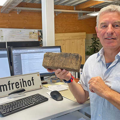 Wolfgang van Bellen präsentiert in seinem Büro ein Stück hölzernes Straßenpflaster, das bei Ausgrabungen in der Liebfrauenstraße zu Tage kam, sowie ein altes Schild der Großbaustelle am Domfreihof.
