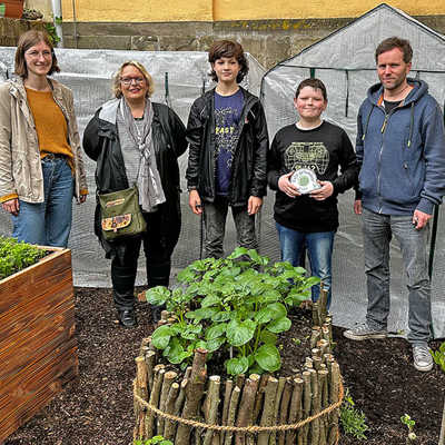 Stolz präsentieren zwei der fleißigen Helfer (Mitte) zusammen mit Stadtjugendpflegerin Michelle Masella, Nicole Helbig, Ortsvorsteherin Trier-Süd, und Christian Schmitt, Leiter des Jugendtreffs „Südpol“ des Palais e.V. (v. l.), das Patenschild von StadtRaum Trier für ihren neuen Garten.