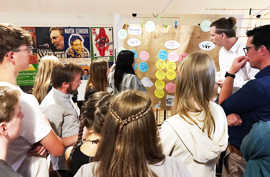 Jugendliche und weitere Teilnehmer der Konferenz schauen auf einem Flipchart mit bunten Post-Its