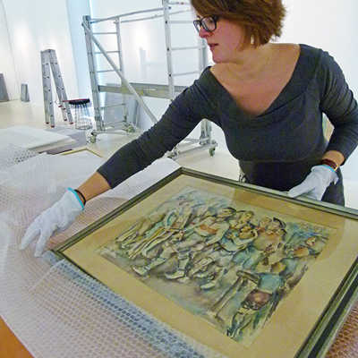 Vorsichtig packt Kuratorin Dorothée Henschel das Bild „Halbzeit – Halbgötter“ von Peter Krisam aus. Foto: Stadtmuseum