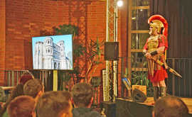 Ein als römischer Soldat verkleideter Schauspieler sthet auf einer Bühne vor Publikum