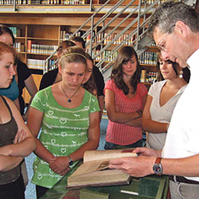 Professor Michael Embach, Direktor der Stadtbibliothek, zeigt Schülerinnen des Angela-Merici-Gymnasiums Originale aus früheren Jahrhunderten. Foto: Stadtbibliothek