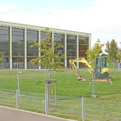 Der am Freitag angelieferte Bagger vor der Grundschule verweist auf den künftigen Standort des Erweiterungsbaus.Foto: Gebäudewirtschaft