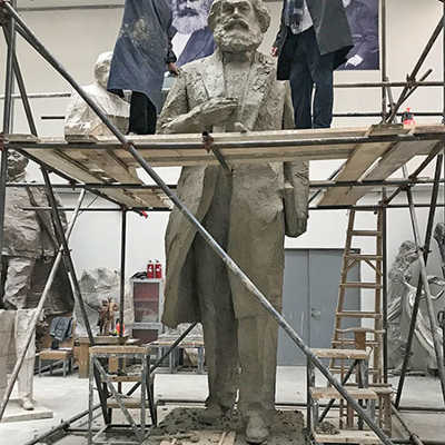 Wu Weishan zeigt Baudezernent Andreas Ludwig in seinem Atelier den Stand der Arbeit an der Karl-Marx-Statue, die ohne Sockel 4,40 Meter hoch ist. Die beiden stehen auf dem Gerüst auf einer Höhe von rund 3,50 Meter. Foto: Elisa Limbacher