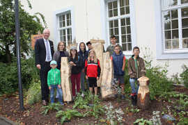 Die Rathaus Kids zeigen OB Wolfram Leibe (l.) die von ihnen bearbeiteten Baumstämme, in die demnächst Wildbienen einziehen sollen.