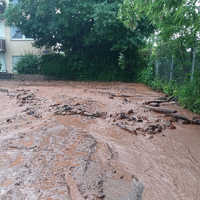 Lokale Sturzflut: Ein über die Ufer getretener Bach sucht sich seinen Weg durch die Straßen. Wasser und Schlamm sammeln sich an Tiefpunkten.