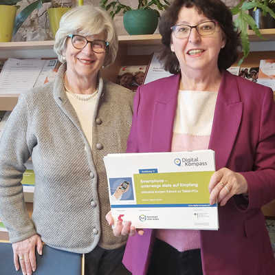 Elisabeth Ruschel, Vorsitzendes des Seniorenbüros, und Maria Dumrese, Verantwortliche für den Digitalkompass in Trier, präsentieren eines der Motive für ihre Werbeaktion.