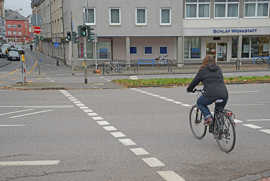 Eine Radfahrerin überquert die Moseluferstraße in Richtung Karl-Marx-Straße