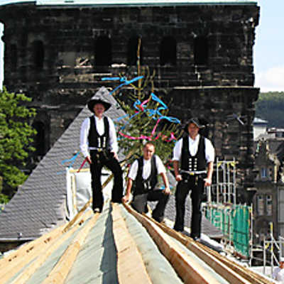 Hoch hinaus: Die Zimmerer Sven Gondring, Enrico Lorenz und Christian Henz (v. l.) von der Firma Holzbau Henz vor dem Richtbaum auf dem Dachfirst des Museums Simeonstift.
