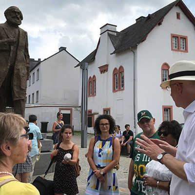 OB Wolfram Leibe versammelt die Teilnehmerinnen und Teilnehmer der Neubürgerführung um Triers neue Sehenswürdigkeit: die Karl-Marx-Statue auf dem Simeonstiftplatz. 
