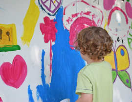 Ein Kind steht  vorneiner Wand mit butnen Malmotiven