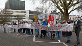 Schülerinnen und Schüler stehen hinter einen meterlangen Banner, auf dem zahlreiche Rote Handabdrücke sind. Neben die Handabdrücke wurden Forderungen geschrieben. Am rechten Bildrand steht Oberbürgermeister Wolfram Leibe.