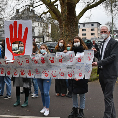 Schülerinnen und Schüler übergeben im Vorfeld des Aktionstags "Red Hand Day" ihre gesammelten Roten Hände an OB Wolfram Leibe (r.).