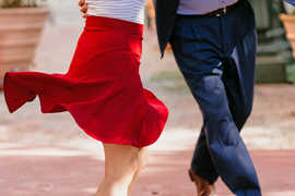 Ein Tanzpaar, von dem man nur die untere Hälfte sieht: sie mit rotem Rock, er mit blauer Hose.