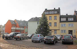 Etwas verloren wirkt der Weihnachtsbaum zwischen den Autos auf der rissigen Asphaltdecke des Platzes an der Numerianstraße in Euren.