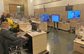 Der Stadtvorstand sitzt im Rathaussaal und sieht auf mehreren Bildschirmen die Ratsmitglieder, die sich per Videokonferenz von zu Hause zuschalten.