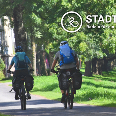 Ein lächelndes Kind mit blauem Fahrrad-Helm umgreift einen Fahrradlenker