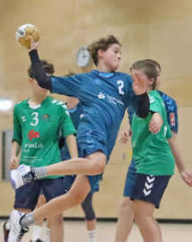 Ein junger Handballer in blauem Trikot setzt zum Wurf an. 