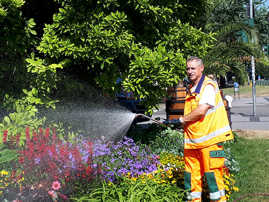 Ein Mitarbeiter des Grünflächenamts bewässert Blumen, Sträucher und Bäume in der Innenstadt. Foto: Presseamt