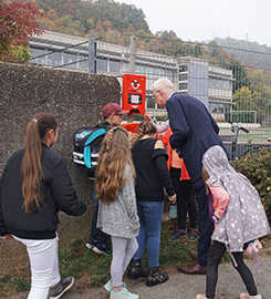 OB Wolfram Leibe nimmt mit den Kindern der Grundschule Reichertsberg die neue Box mit Plastiktüten für Hundehaufen in Augenschein.