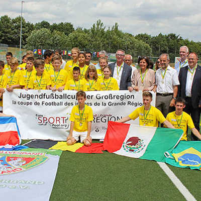 Stolz präsentieren die jungen Kicker ihre Medaillen und zahlreiche Flaggen beim Abschlussfoto mit OB Klaus Jensen und Ministerpräsidentin Malu Dreyer (zweite Reihe, 4. und 5. v. r.). 