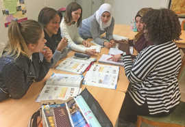 Teilnehmerinnen eines Sprachkurses arbeiten gemeinsam an der Lösung einer Aufgabe aus ihrem Lehrbuch.