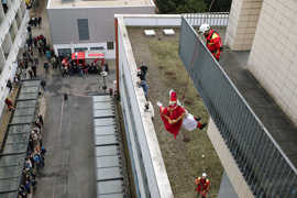 Ein Feuerwehrmann im Nikolauskostüm wird in einen Hof abgeseilt.