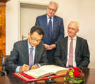 Generalkonsul Shunqing Wang trägt sich im Beisein von OB Wolfram Leibe (r.) und Baudezernent Andreas Ludwig ins Gästebuch ein.