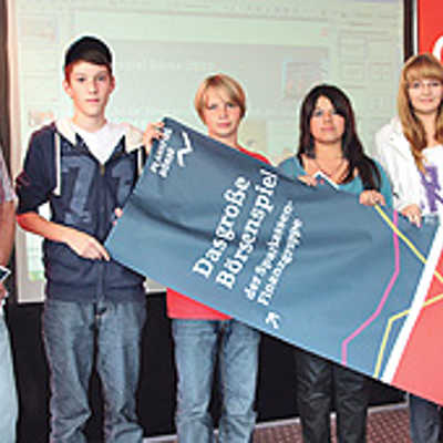 Schüler aus der Region Trier präsentieren mit einem Lehrer des Werbebanner des Planspiels Börse.Foto: Sparkasse