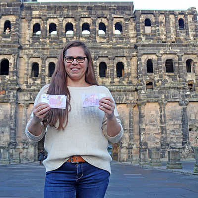 TTM-Abteilungsleiterin Caroline Baranowski zeigt die violette Banknote vor dem steinernen Original. Foto: TTM
