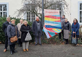 Eine große Gruppe Menschen präsentiert vor dem Rathaus eine der Fahnen