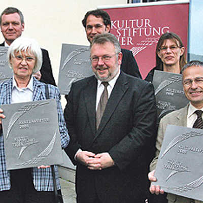Dr. Olaf Hornfeck (SWT), Horst Schreiber (Volksbank), Andrea Kupfer (Bob Design, hinten, v. l .), Gisela Burg (links vorne) und Hwk-Präsident Rudi Müller (rechts vorne) präsentieren die von Ulrich Holkenbrink (vorne Mitte) überreichten Stifterplatten.