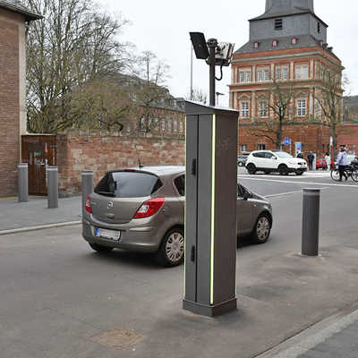 Ein Auto durchfährt eine Pollerlinie mit versenkbaren Elementen. Im Vordergrund steht ein Steuerkasten zur Bedienung der Poller