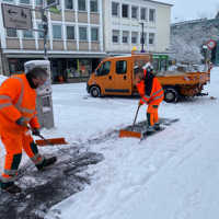 Zwei städtische Mitarbeiter räumen den Heinz-Tietjen-Weg mit Schneeschiebern.