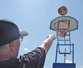 Ein Man mit Schirmmütze wirft einen Ball auf einen Basketballkorb.