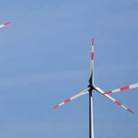 Rot-weiß gestreifte Rotorblätter von drei Windrädern vor einem blauen Himmel